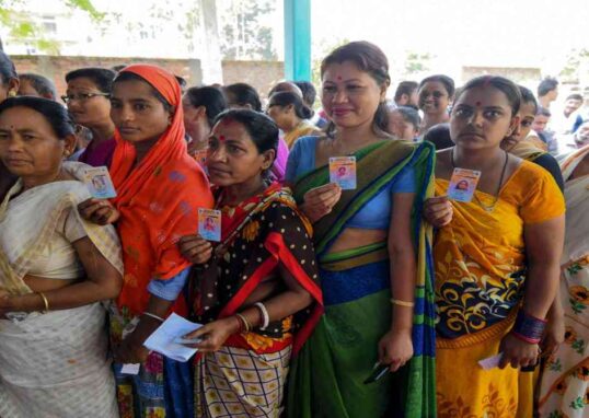 मतदान केंद्र पर वोट डालने के लिए खड़े लोग, लोकतांत्रिक भागीदारी का प्रतीक