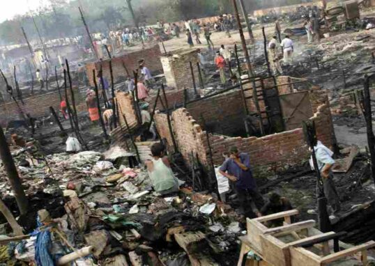 दिल्ली के रोहिणी क्षेत्र में रात के समय झुग्गियों में लगी आग, जहां दमकल विभाग आग बुझाने में जुटा है।