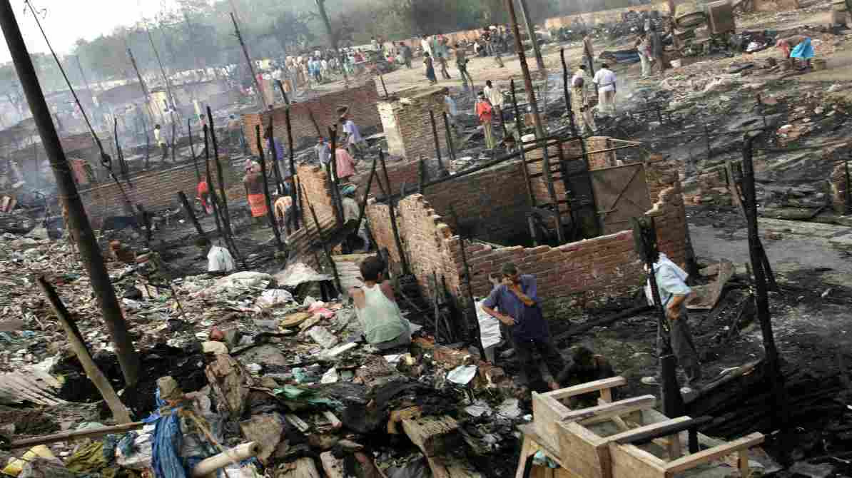 दिल्ली के रोहिणी क्षेत्र में रात के समय झुग्गियों में लगी आग, जहां दमकल विभाग आग बुझाने में जुटा है।