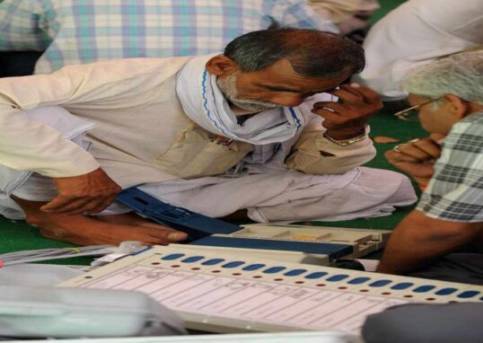 मतदान केंद्र पर ईवीएम मशीन की जांच करते अधिकारी, जहां बटन साफ और सुरक्षित दिख रहे हैं