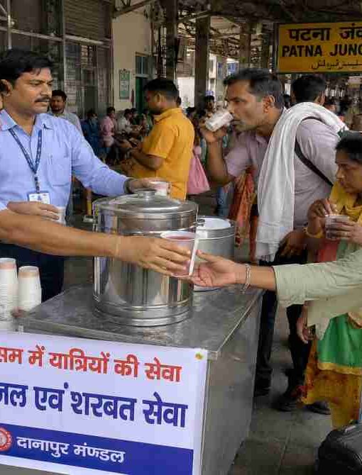 भीषण गर्मी के दौरान पटना जंक्शन प्लेटफॉर्म पर यात्रियों को शरबत और ठंडा पानी बांटते रेलवे कर्मचारी का दृश्य।